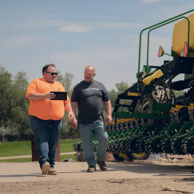Two people walking a farm site while planning a shoot on a tablet
